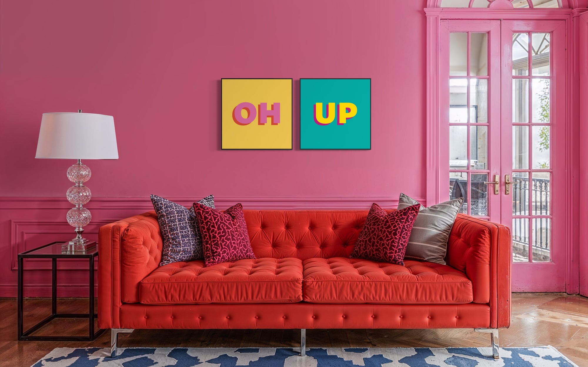 Red sofa in a room with pink walls, colorful artwork, and a lamp.