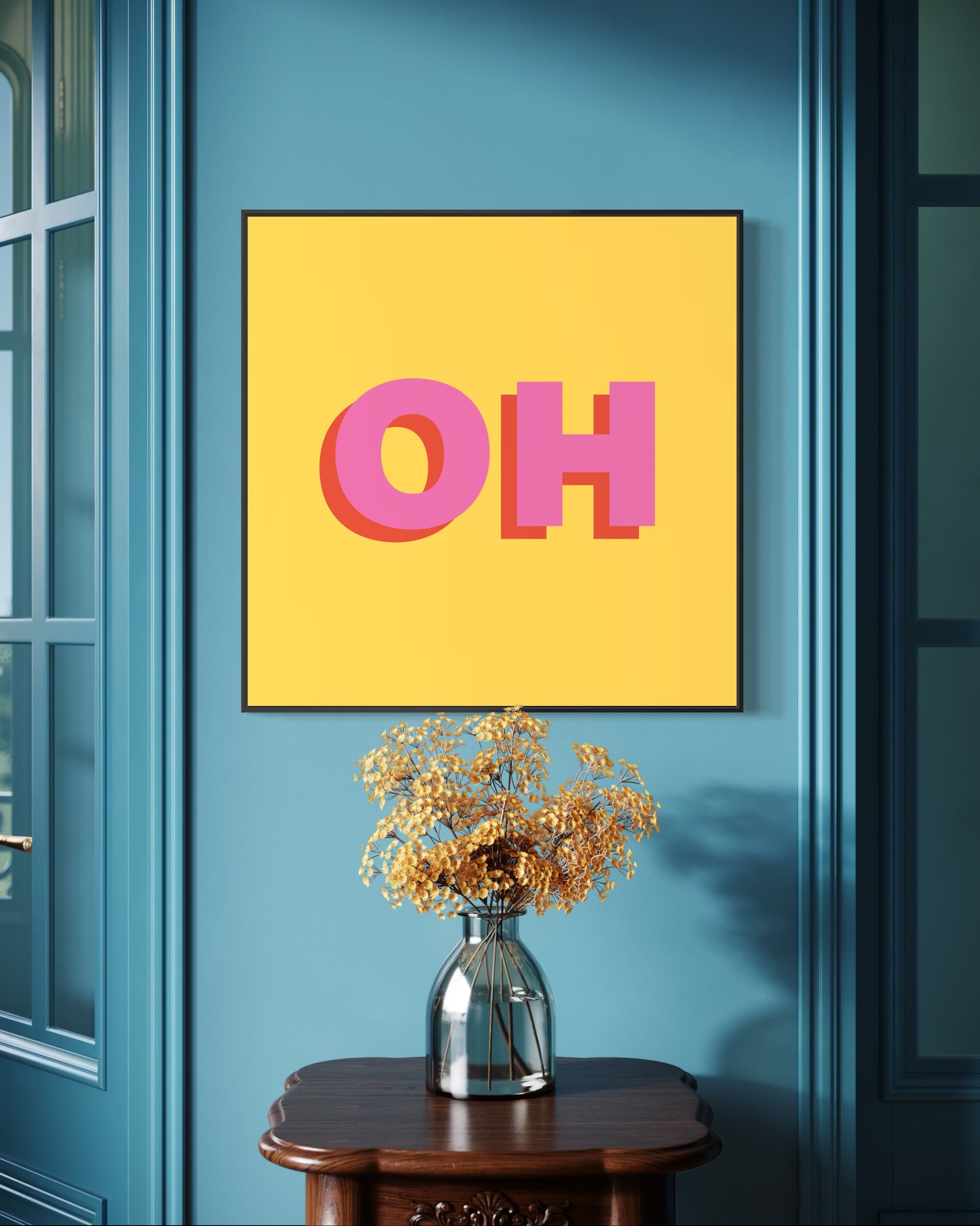 Yellow frame with pink 'OH' letters on a blue wall above a vase with flowers.